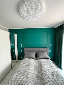 sypialnia z łóżkiem i zieloną ścianą w obiekcie Awenturyn Apartament SAGARIS Dziwnów w Dziwnowie