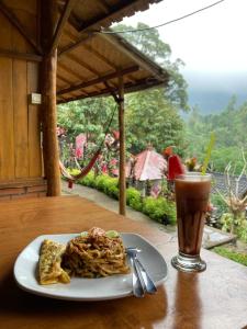 a plate of food on a table next to a drink at Friendly Homestay Lemukih in Singaraja +71 photos