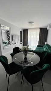 salon ze stołem i zielonymi krzesłami w obiekcie Awenturyn Apartament SAGARIS Dziwnów w Dziwnowie