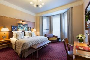 a hotel room with a bed and a desk and a chair at Hôtel Barrière Le Westminster in Le Touquet-Paris-Plage