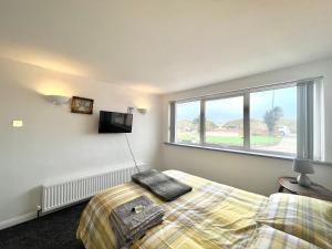 a bedroom with a bed and a tv and a window at Beach Front Apartment with Free Parking, St Annes in Lytham St Annes