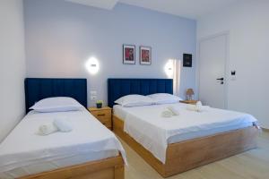 2 camas en un dormitorio con paredes azules y blancas en Twins Hotel en Ksamil