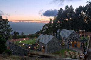 a house on a hill with a sunset in the background at Palheiros do Serrado by Real Vision in Estreito da Calheta