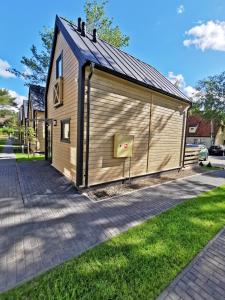 un gran edificio de madera con una puerta en una acera en Ośrodek Wypoczynkowy Merkury, en Mrzeżyno