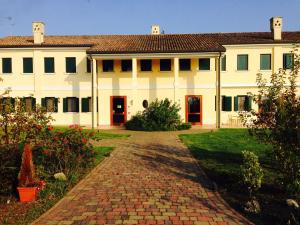 une grande maison blanche avec une allée en briques dans l'établissement Il Paradello Albergo, à Porto Levante