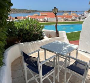 a dining room with a table, chairs and a pool at Apartamentos El Bergantin Menorca Club in Fornells
