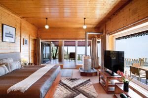 卡纳塔尔Avalon Cottages, Kanatal by Leisure Hotels的一间配有一张大床和一台平板电视的卧室