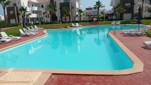 a large swimming pool with lounge chairs in a resort at Résidence Perla appart 2 pièces in Saïdia