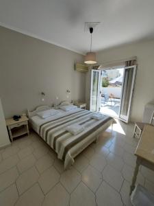 a bedroom with a large bed and a large window at Alkyon Hotel in Kamari