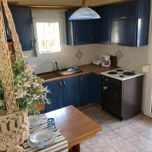 eine Küche mit blauen Schränken, einem Tisch und einem Herd in der Unterkunft Cookoo Villas in Kriopigi