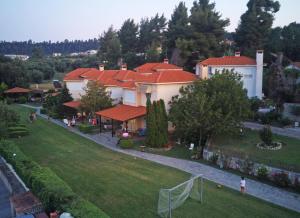 ein großes Haus mit roten Dächern auf einem grünen Rasen in der Unterkunft Cookoo Villas in Kriopigi