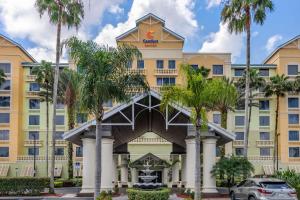 un grand bâtiment jaune avec des palmiers devant lui dans l'établissement Comfort Suites Maingate East, à Orlando