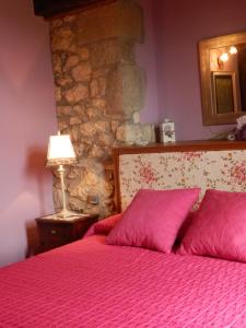 1 dormitorio con 1 cama con sábanas rosas y pared de piedra en Posada El Salin, en Muñorrodero