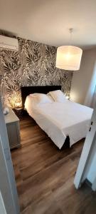 - une chambre avec un lit blanc et un mur dans l'établissement La Maison d'Alphonse, à Avignon