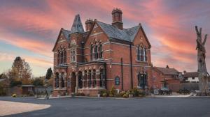 a large red brick building with a sunset at The Godwins in Hereford