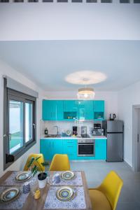 a kitchen with blue cabinets and a table with yellow chairs at Amarynthos Maisonettes in Amarynthos