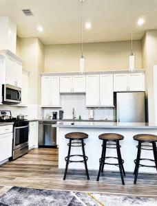 a kitchen with white cabinets and three bar stools at Modern Style Relaxation in Houston, Texas in Houston