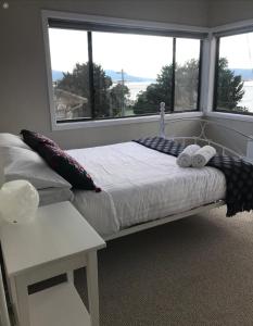 a bed with two pillows and a table in front of a window at 3 Bedroom Lakeview Cottage with Drying/Bike Room in Jindabyne