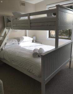 um quarto com 2 beliches e lençóis brancos em 3 Bedroom Lakeview Cottage with Drying/Bike Room em Jindabyne