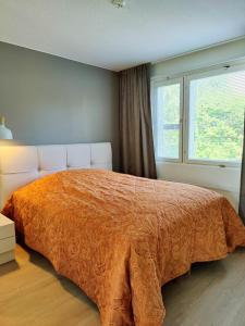 a bedroom with a bed with an orange comforter and a window at Lovely cityhome in Rovaniemi