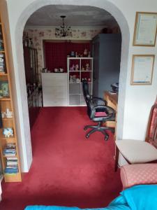 una oficina con silla y alfombra roja en Single bed in large room, Sofa, netflix, garden view, patio door & seating, en Poole