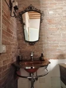 a bathroom with a sink and a mirror on a brick wall at Corte di Maggio B&B Country House in Imola