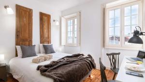 a bedroom with a bed with a blanket and a desk at RUN Aveiro in Aveiro