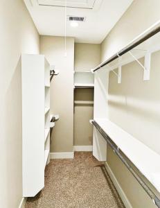 einen begehbaren Kleiderschrank mit weißen Schränken und Regalen in der Unterkunft Modern Style Relaxation in Houston, Texas in Houston