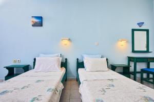 Hotel Glaros في ديافاني: سريرين في غرفة بجدران زرقاء