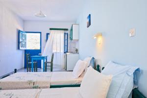 2 łóżka w pokoju z niebieskimi ścianami w obiekcie Hotel Glaros w mieście Diafani