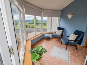 a room with two chairs and a table and windows at Braeside Farm House in Ballymena