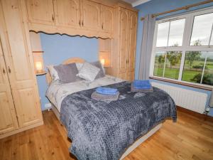 a bedroom with a bed and a large window at Braeside Farm House in Ballymena
