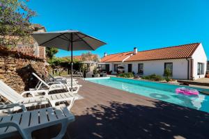 a pool with chairs and an umbrella next to a house at Casa do Casal - Country House with Swimming Pool in Viana do Castelo