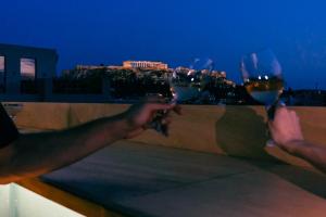 Dos personas sosteniendo copas de vino con vistas a la ciudad en Mosaikon, en Atenas