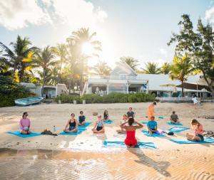 a group of people sitting in the sand on a beach at Astroea Beach Hotel in Blue Bay +59 photos