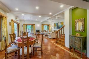 a dining room and living room with green walls at SaffronStays Windermere, Lonavala - luxury villa with heated pool, projector room and indoor games in Lonavala