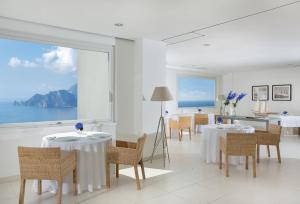 une salle à manger avec des tables et des chaises ainsi qu'une grande fenêtre dans l'établissement Relais Blu, à Massa Lubrense