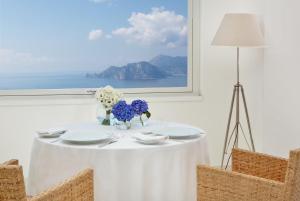 a white table with plates and flowers on it at Relais Blu in Massa Lubrense