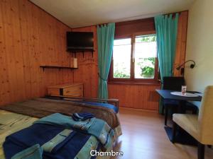 1 dormitorio con cama, mesa y ventana en Chez l'Eveline, en Les Bois