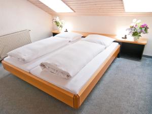 a large bed with white sheets and pillows at Landhaus am Kienberg in Pfronten