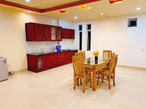 a kitchen with red cabinets and a wooden table and chairs at GreenHome Hotel in Hai Phong