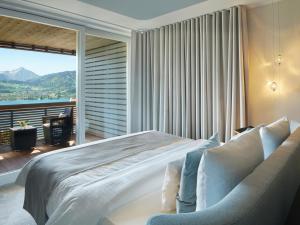 a hotel room with a large bed and a large window at Das Tegernsee in Tegernsee