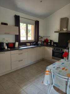 cocina con armarios blancos, fregadero y ventana en hébergement figari en Figari