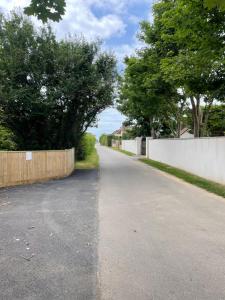 an empty road with a fence and trees on the side at The Attic Suite Selsey in Selsey