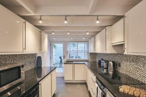a kitchen with white cabinets and black counter tops at The New Pin in St Ives