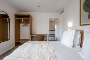 a bedroom with a large white bed and a chair at The Originals Boutique Hôtel Amiens Sud in Amiens