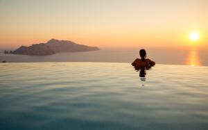 a woman sitting in a infinity pool watching the sunset at Relais Blu in Massa Lubrense