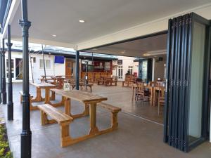eine Cafeteria mit Holzbänken, Tischen und Tischen in der Unterkunft Samoa Hotel in Moorreesburg