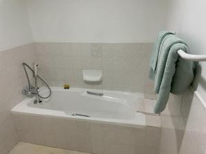 a white tub in a bathroom with a green towel at Samoa Hotel in Moorreesburg