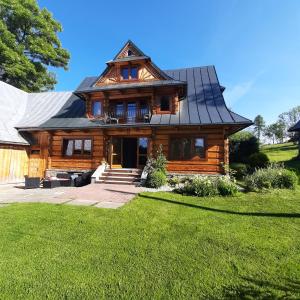 a log home with a gambrel roof at Miodowa Chata Pokoje Gościnne in Bustryk